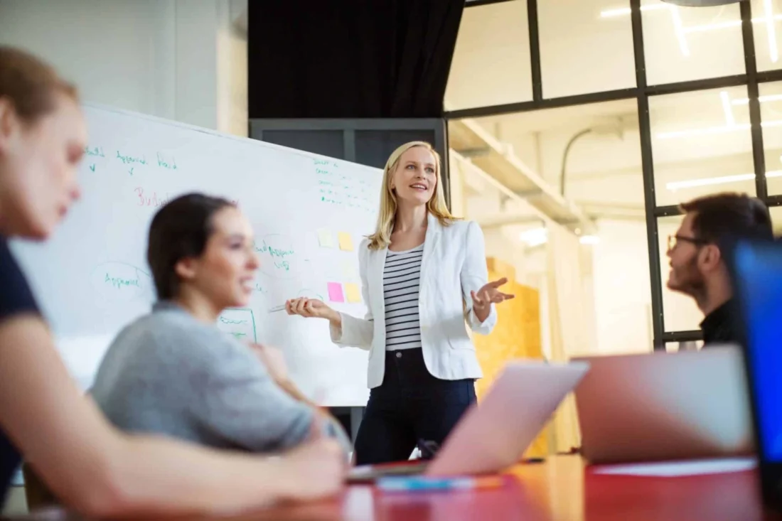 A woman leads a collaborative meeting in a modern office, illustrating the strategic planning behind B2B tech PR agency services.