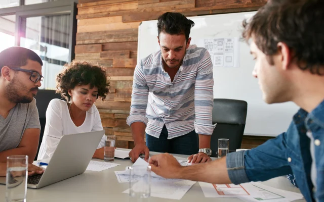 A diverse team of professionals in a modern office collaborating on business strategy, embodying credibility that drives B2B tech growth.