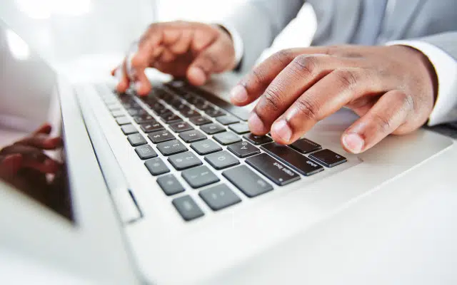 Close-up of a professional typing on a laptop keyboard, representing content creation and Generative Engine Optimization for B2B tech.