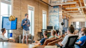 A startup founder leads a team meeting in a modern office, presenting a slide deck while discussing flexible PR contracts for startups.