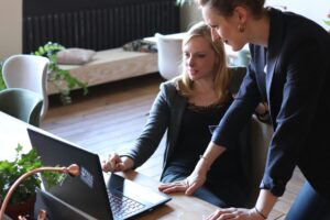 Two business professionals collaborate at a laptop, discussing B2B tech media coverage strategies.