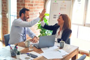 Two business professionals in a modern office celebrate success with a high-five, symbolizing teamwork and achievement—an image representing how to use case studies in B2B tech PR to build credibility and growth.