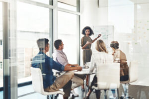 Team meeting in a glass conference room reviewing strategy and performance metrics related to PR ROI measurement.