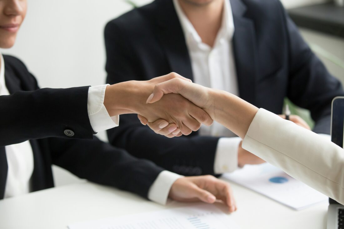 Professionals shaking hands during a meeting, representing how to evaluate B2B technology PR agencies and choose the right strategic partner.