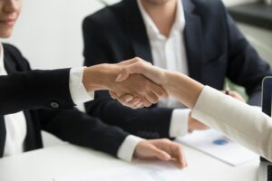 Professionals shaking hands during a meeting, representing how to evaluate B2B technology PR agencies and choose the right strategic partner.