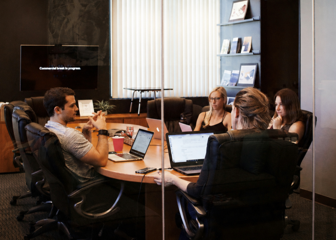 Team meeting in a glass-walled conference room discussing internal expertise and AI visibility for B2B technology marketing.