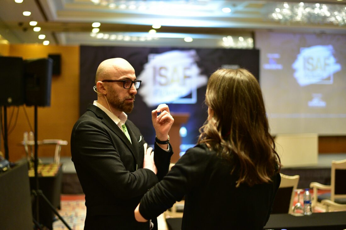 Two business professionals discuss a presentation at a conference, illustrating authentic thought leadership through direct conversation and expert exchange.